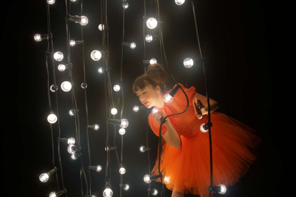 Isa im orangenen Kleid und mädchenhafter Frisur erzählt von ihrem Vater